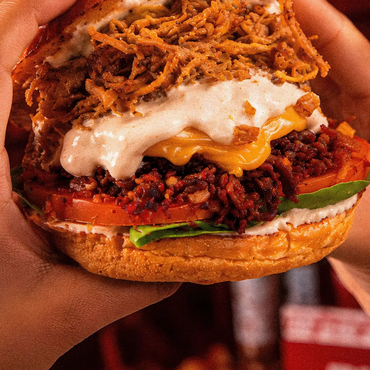 Burger Dakota sostenida en mano frente al letrero de neón del local
